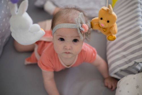 stock photo of infant in crib with stuffed animal mobile