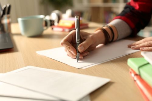 Hand holding pen writing in notebook