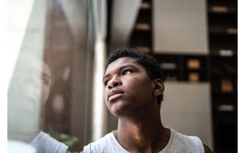 stock photo of sad young man looking out the window. 