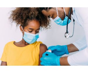 Doctor puts on band-aid for girl after giving her vaccine.