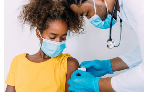 Doctor puts on band-aid for girl after giving her vaccine.