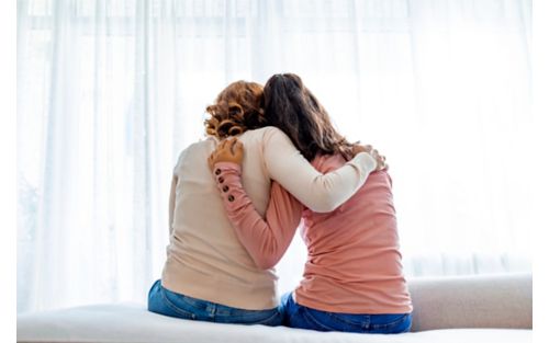 Rear view of mother and daughter hugging.