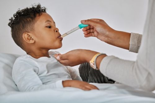 A doctor feeds a young child medicine