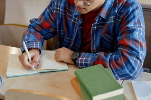 Male teen writing in notebook