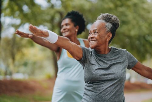 Two women doing warrior pose outside