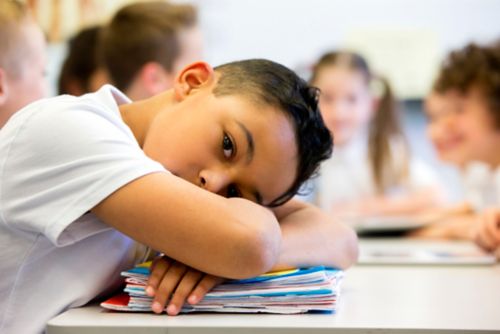 Sad child with head on desk
