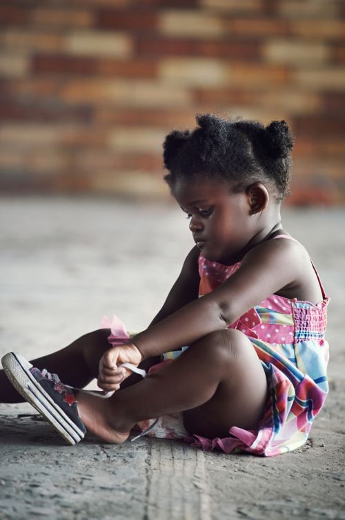Little girl sits while putting on shoes
