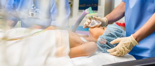 Blurred shot of a child with oxygen mask lying on bed in operating room