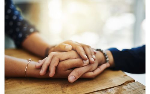 Closeup of two unrecognizable people holding hands in comfort