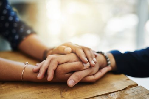 Closeup of two unrecognizable people holding hands in comfort