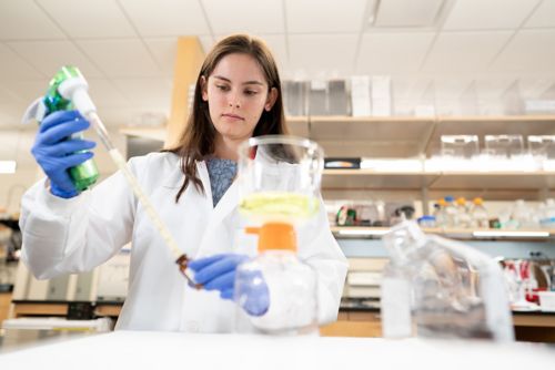 woman in lab pouring something from one container to another