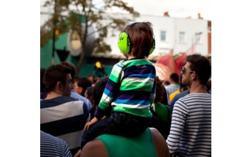 Child wears protecting hearing while attending outdoors event.