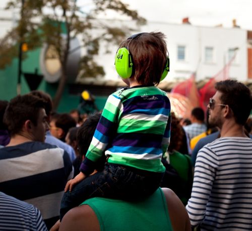 Child wearing protective hearing device while at outdoors event.