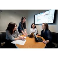 Four women talk in front of screen