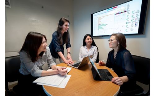 Four women talk in front of screen