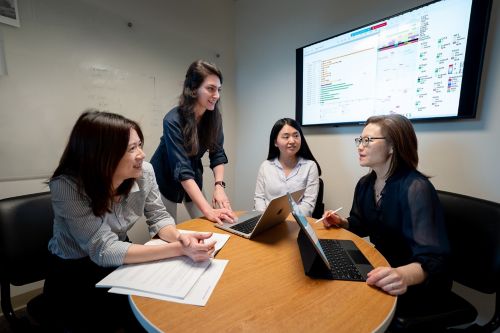 Four women talk in front of screen