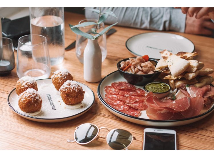 image of table with plate of charcuterie Sunglasses and phone on the table