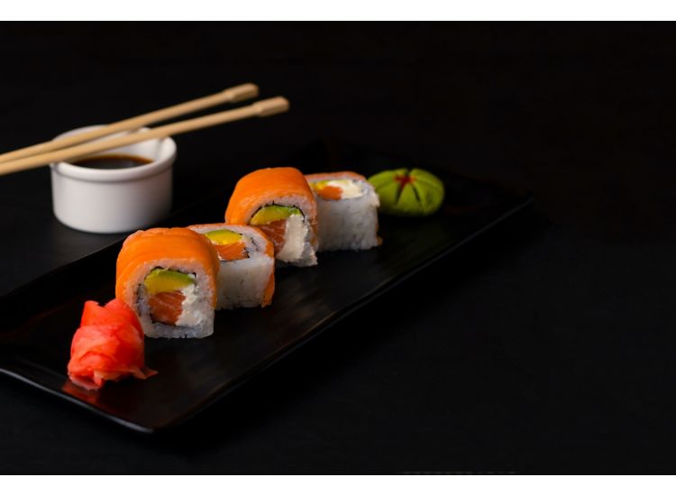 Image of several pieces of sushi on a table next to a container of sauce and chopstick