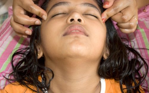 Child getting head massage from mother