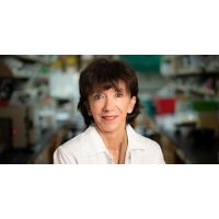 Martine Roussel, PhD, stands for a portrait with her lab blurred out in the background.