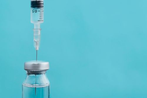 Photo of syringe needle withdrawing medicine from glass vial