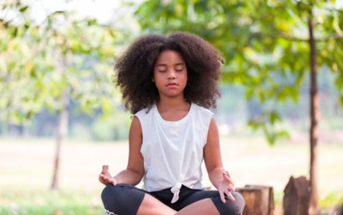Teen girl meditating outdoors
