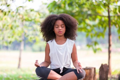 Teen girl meditating outdoors