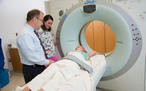 Patient receiving proton therapy treatment while two clinicians look on