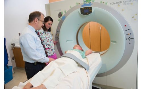 Patient receiving proton therapy treatment while two clinicians look on