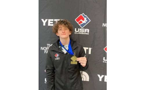 Micah holds up medal from climbing paralympics