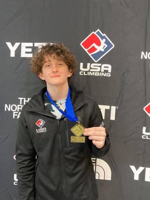 Micah sostiene su medalla de escalada en roca