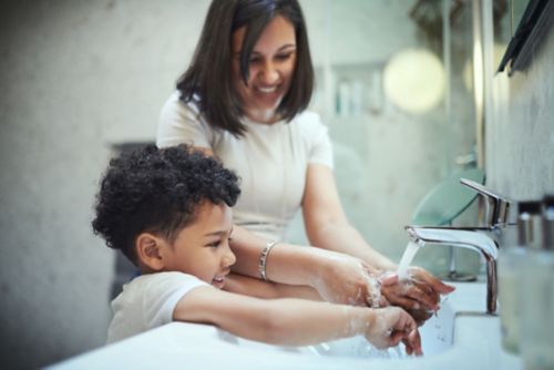 Shot of a young boy and his mother washing their hands in the bathroom sink at home stock photo