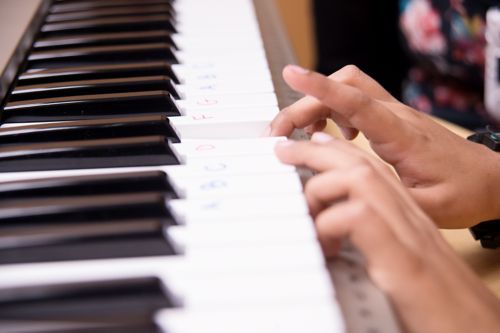 ребенок с онкологическим заболеванием нажимает на клавиши инструмента, на которых написаны названия нот