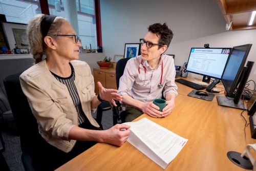 Women and man  talking at a desk in front of computers