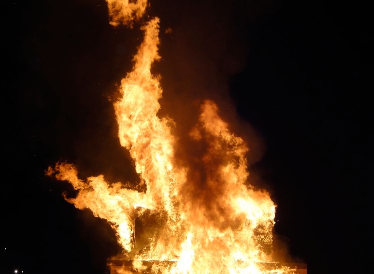 People looking at a large bonfire at night.