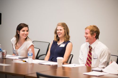 two women and one man sitting at a table laughing at something