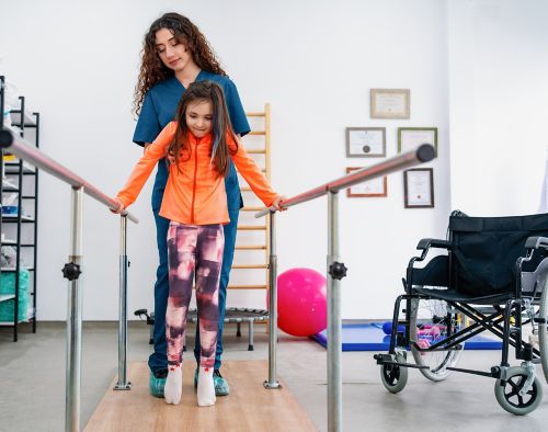 Paciente joven femenina que hace fisioterapia en una clínica con ayuda de un terapeuta.