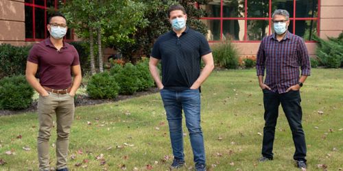 Three men wearing masks standing outside