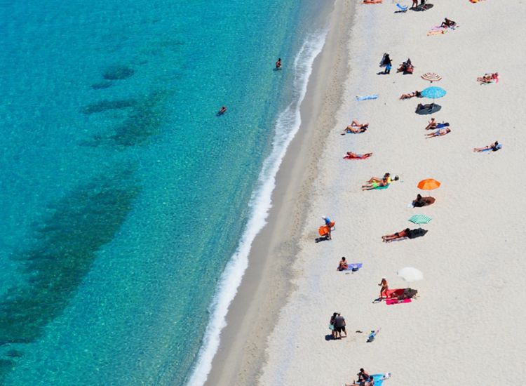 Aerial view of white sandy beach and aqua blue ocean with beach goers