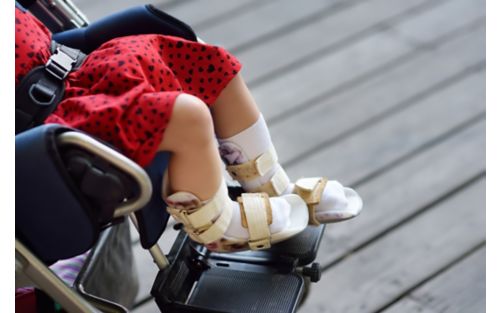 Child in wheelchair wearing orthotics gear.