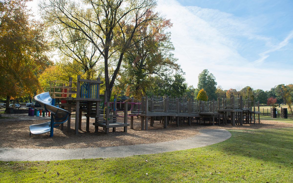 Rope structure in a playground surrounded by trees on a sunny day.