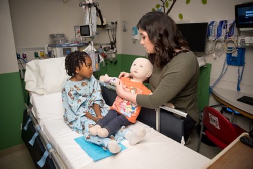 Un especialista en vida infantil le enseña a un paciente joven sobre un procedimiento médico. 