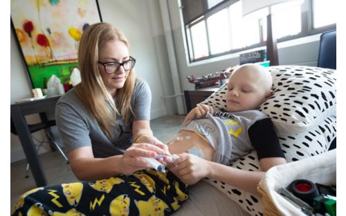 Mother puts liquid food into G tube attached to son's stomach