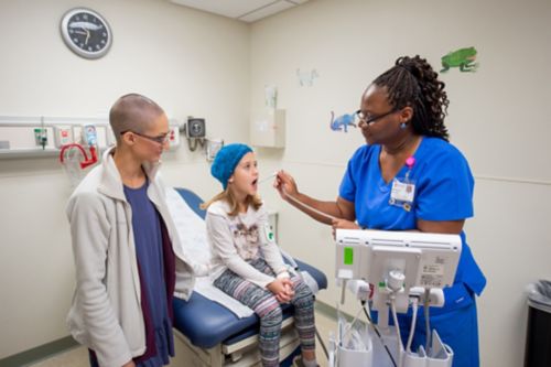 La fièvre neutropénique chez un enfant atteint d'un cancer peut engager le pronostic vital et doit être traitée comme une urgence médicale. Une infirmière prend la température d'une jeune patiente tandis que sa mère se tient à ses côtés.