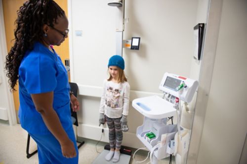 Childhood cancer patients at risk for developing growth hormone deficiency should have an exam that includes measurement of height and weight every six months until growth is completed. In this image, cancer center staff measures a survivor’s weight.