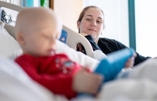 Cuando un hijo tiene cáncer, los desafíos que enfrentan los padres pueden ser abrumadores. Aquí, una madre observa a un niño recostado en una cama de hospital.