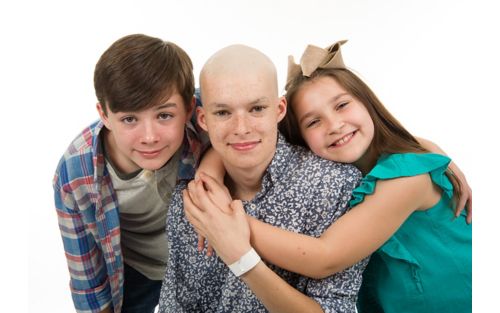 Male teen cancer patient with brother and sister hugging him