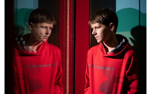 Male teen looks at his reflection in glass window