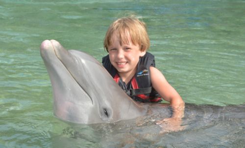 Dziecko z nowotworem wieku dziecięcego pływa z delfinem