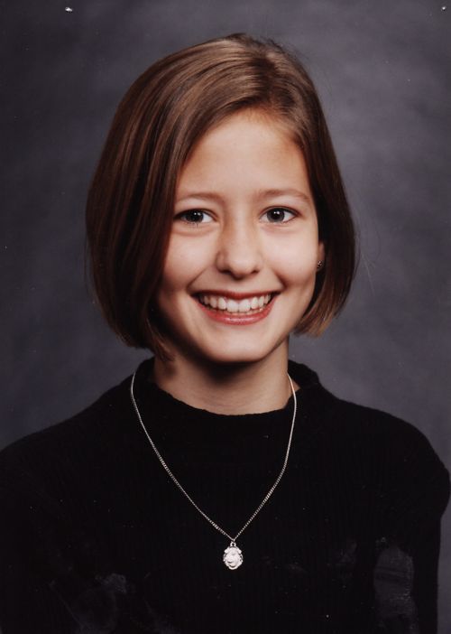 Portrait of the patient in a black sweater wearing a necklace and with hair down to her chin.